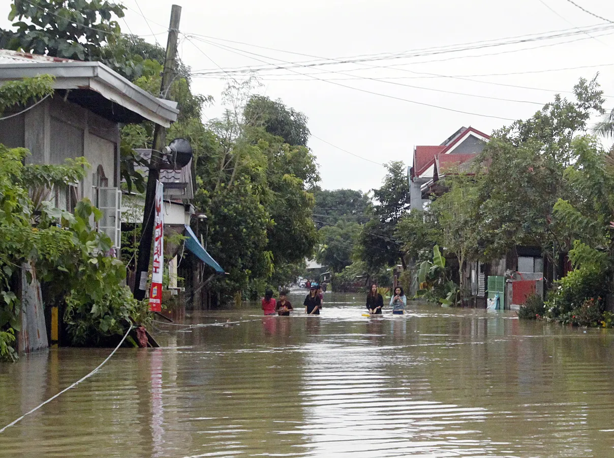 Residents wade along a flooded street in Bulan, Sorsogon province, Philippines, on Dec. 30