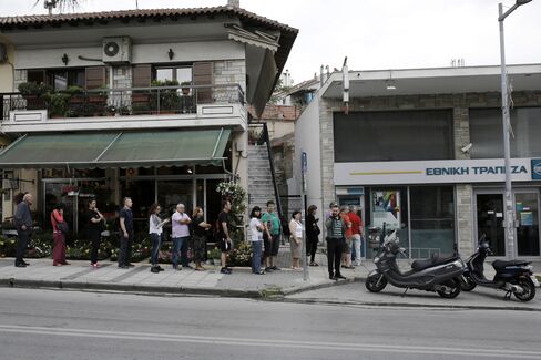 Customers queue to use an automated teller machine (ATM) outside a National Bank of Greece SA bank branch in Thessaloniki, Greece, on Saturday, June 27, 2015.