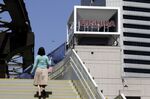 A pedestrian walks up a flight of stairs near signage for Toshiba Corp. displayed at the company's headquarters in Tokyo, Japan, on Wednesday, April 7, 2021. Toshiba surged its daily limit of 18% after confirming it received an initial buyout offer from CVC Capital Partners, setting the stage for potentially the largest private equity-led acquisition in years.