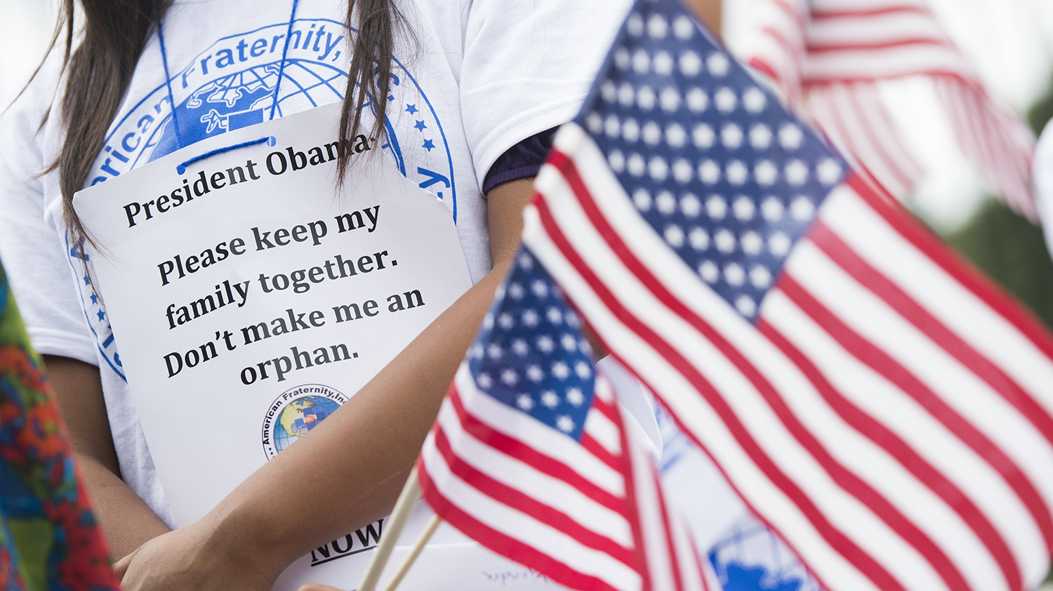 A child whose father was deported, holds US flags during a protest in response to US President Barack Obama's delay on immigration reform in front of the White House in Washington, DC, September 8, 2014.
