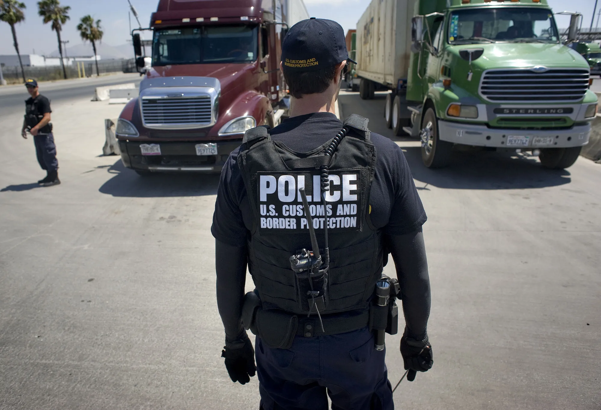 A US Customs and Border Protection officer stands in front of a line of trucks waiting for inspection at the Otay Mesa Cargo Port of Entry in San Diego, California.
