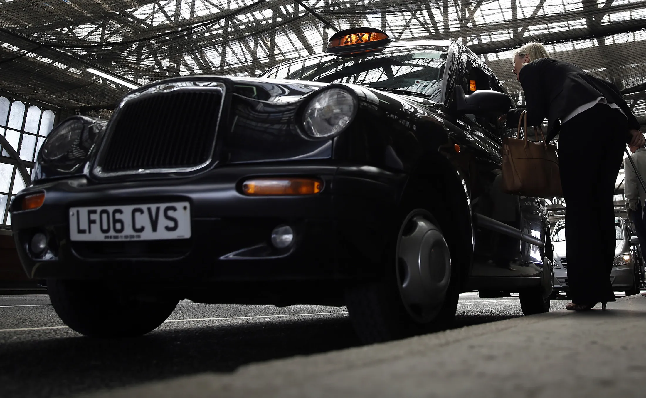 Passengers prepare to board a black London cab outside Waterloo train station.
