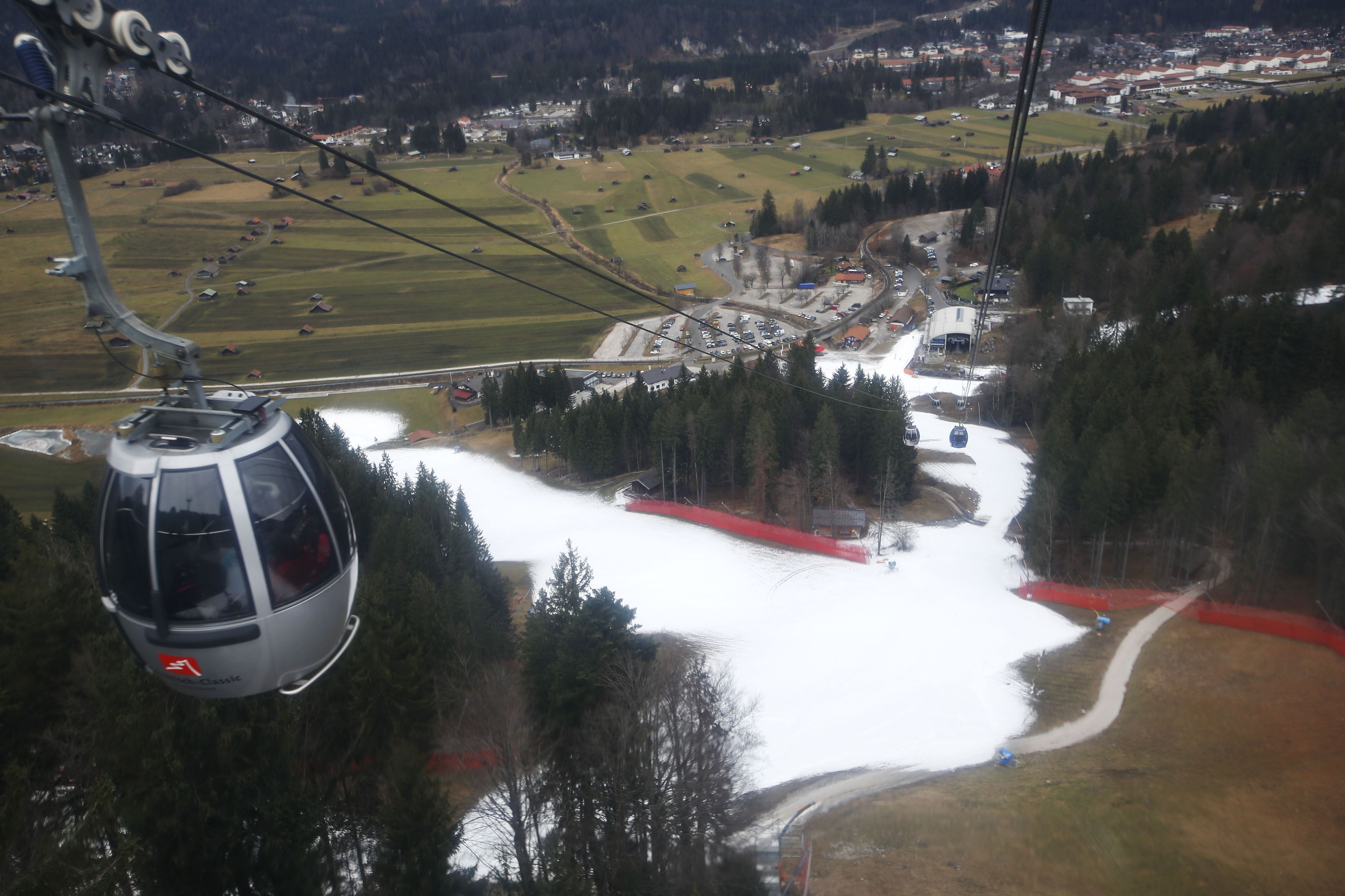 Cable car cabins travel over artificial snow on a ski slope at the Alpine skiing resort in Garmisch-Partenkirchen, Germany, on Jan. 8, 2020. Like other resorts at relatively low altitude, global warming has left its mark on Garmisch-Partenkirchen — the site of the 1936 Winter Olympics—putting the town’s identity and affluence at risk.