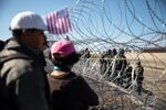 People stand in front of barbed wire across from U.S. Customs and Border Protection (CBP) officers along the US and Mexico border in Tijuana, Mexico.