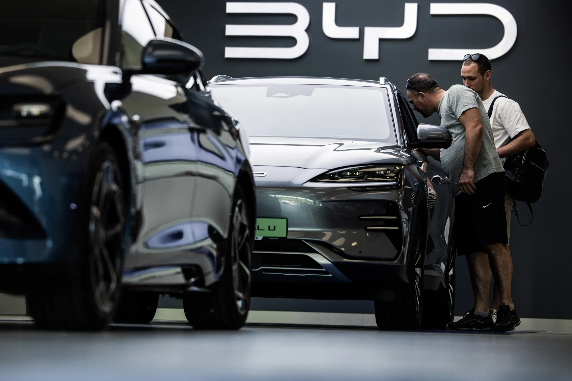 Customers look at electric vehicles at a BYD showroom.