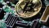 A coin representing Bitcoin cryptocurrency sits on a computer circuit board in this arranged photograph in London, U.K., on Tuesday, Feb. 6, 2018.