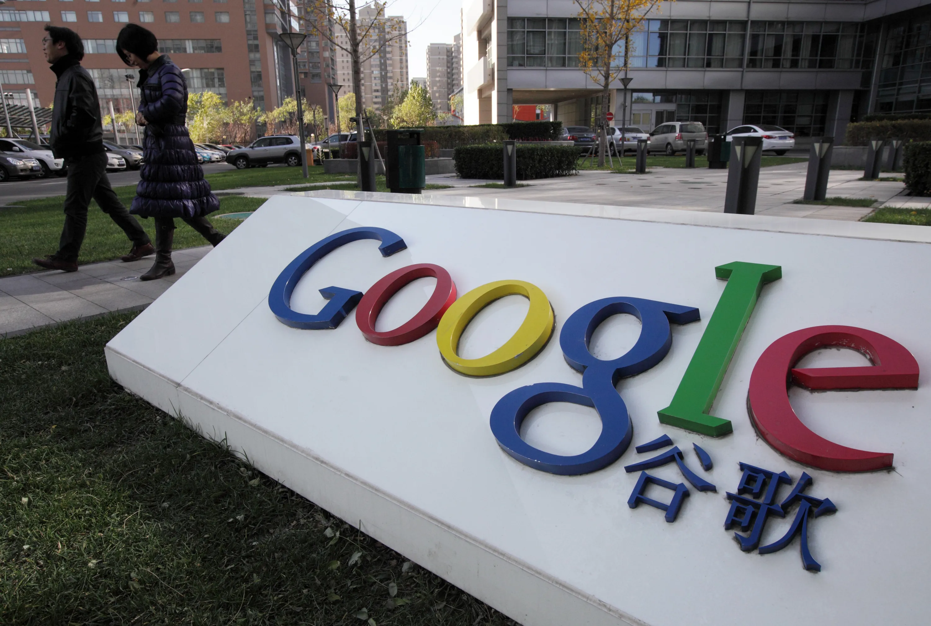 Pedestrians walk past the Google Inc. logo displayed outside the building housing the company's China headquarters in Beijing.