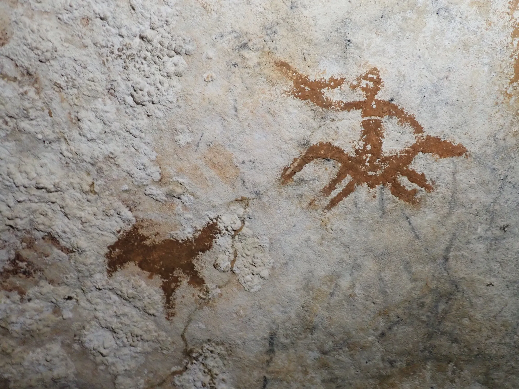 Faint outline of 67,800-year-old hand stencil in Sulawesi is seen between two newer images.