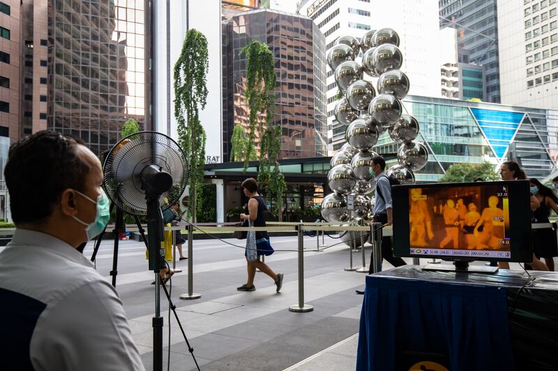 Workers monitor office workers passing through a gate in Singapore on Feb. 10. Image: SeongJoon Cho/Bloomberg