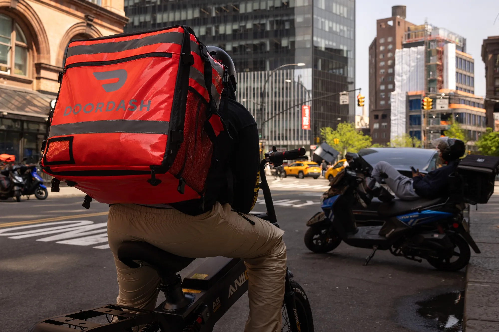 A delivery worker carries a DoorDash bag in New York.