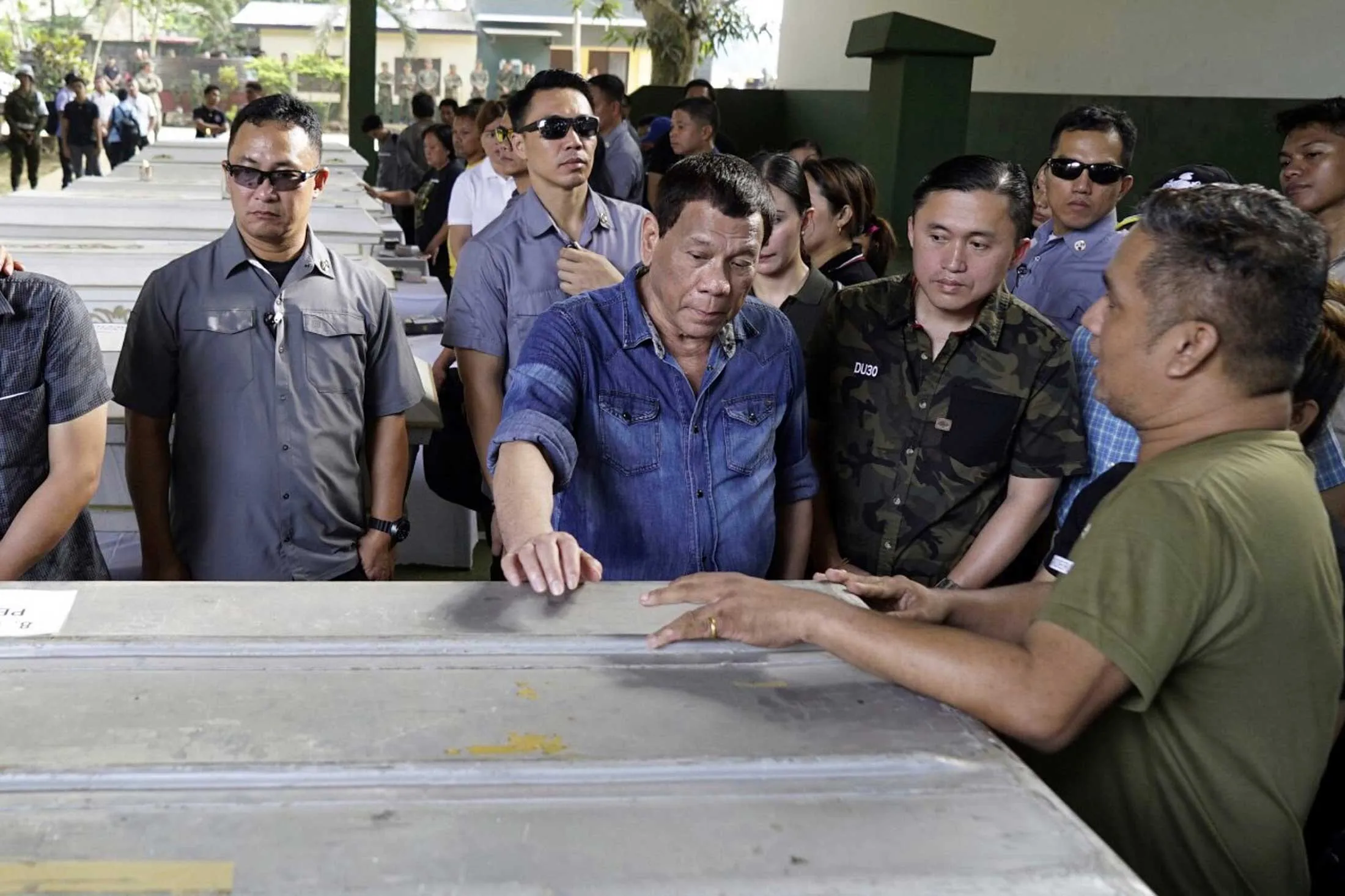 Philippine President Rodrigo Duterte (center) with the caskets of victims killed in a bombing in Sulu province.