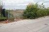 Same field, but with even more giant overgrowth and garbage strewn outside fence gate