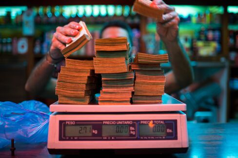 A bakery manager weighs banknotes in Caracas.
