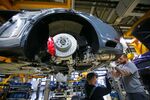 Employees secure the exhaust unit to a Porsche 911 luxury automobile on the assembly line at Porsche AG's factory, operated by Volkswagen AG, in Stuttgart.