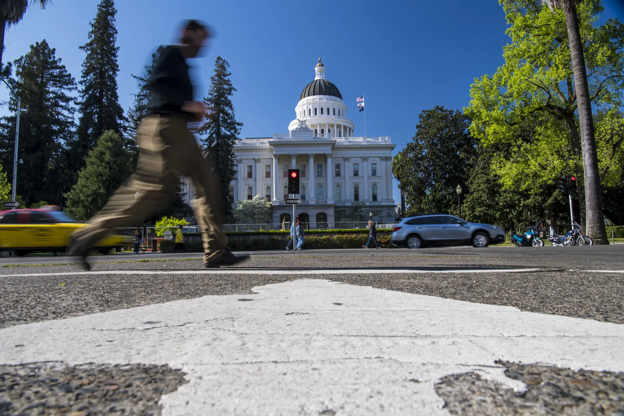 Pedestrians walk past the California State Capitol building in Sacramento.