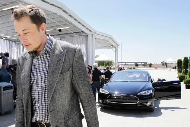 Tesla CEO Elon Musk walks past the Tesla Model S after a news conference at the Tesla factory in Fremont, Calif.
