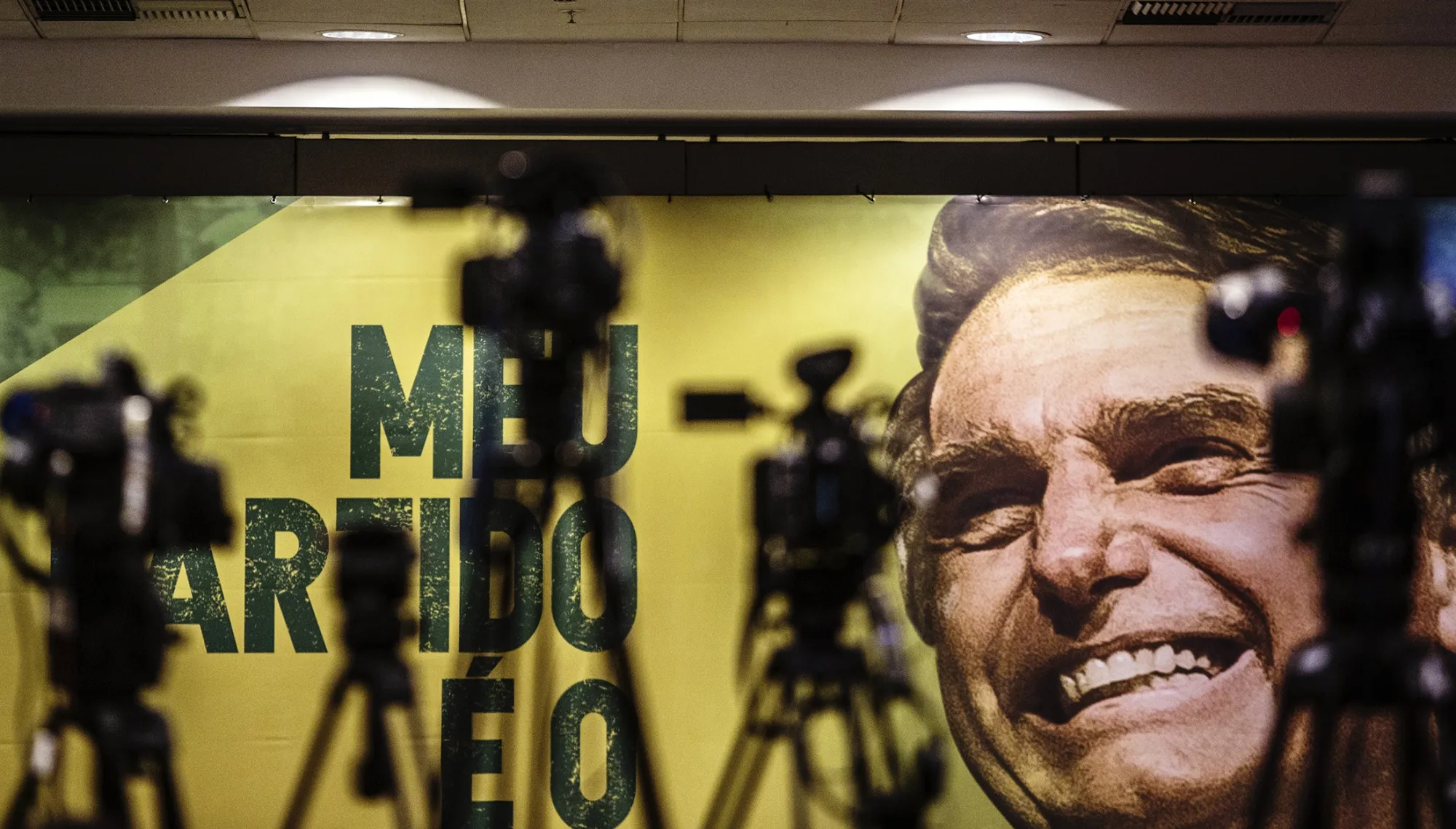 Cameras and tripods stand in front of a banner featuring Jair Bolsonaro.
