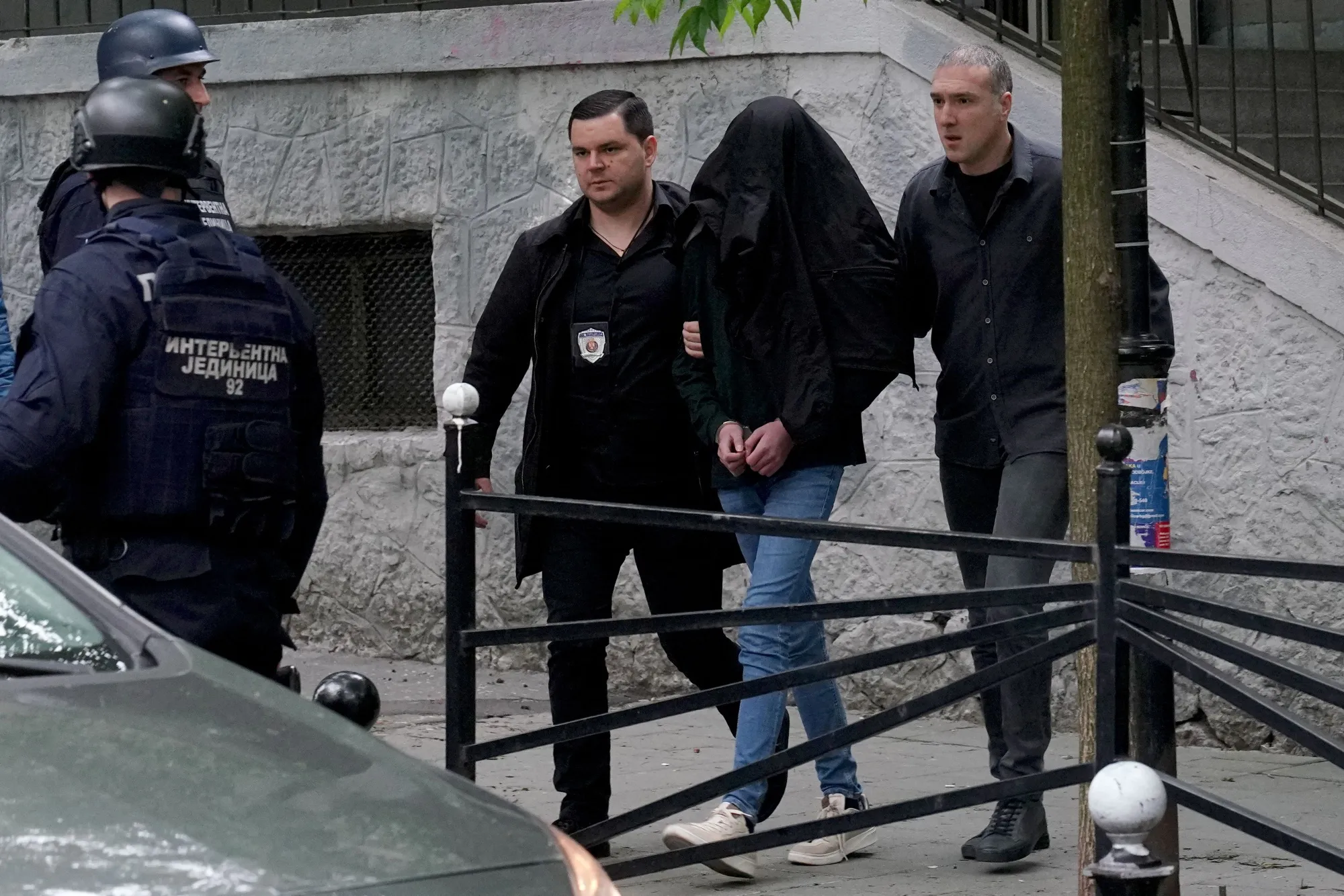 Police officers escort a seventh grade student who is suspected of firing several shots at a school in Belgrade.