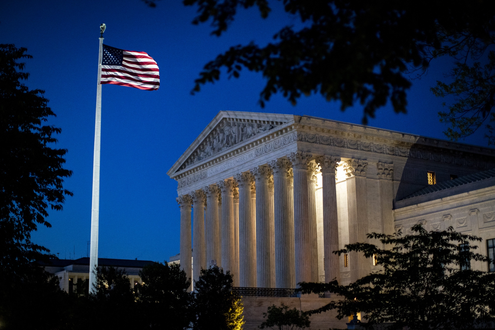 An American flag flies outside the U.S. Supreme Court as it stands illuminated at night in Washington, D.C. on May 4, 2020.&nbsp;