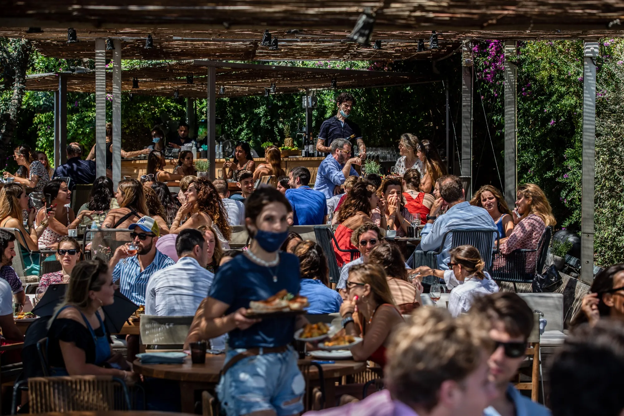 Customers sit outside under a covered terrace at a restaurant at Barceloneta beach in Barcelona, Spain, on&nbsp;June 28.