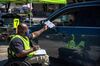 A worker wearing a protective mask takes a ballot from a voter at a drive-through mail ballot hand delivery center in Austin, Texas, U.S., on Friday, Oct. 2, 2020.