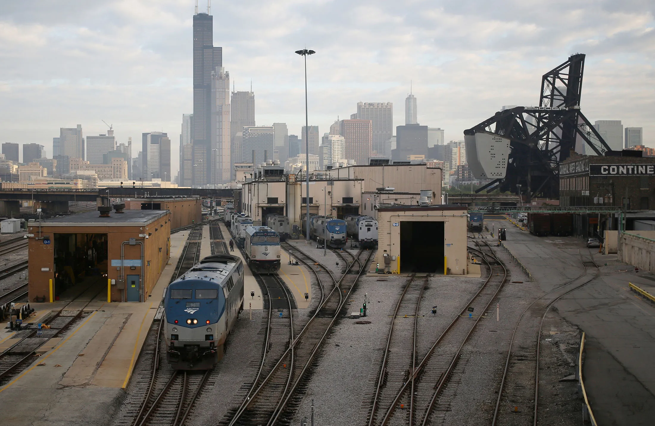 Amtrak locomotives sit parked at the 18th Street locomotive shop as the Willis Tower stands in the skyline of Chicago, Illinois, U.S., on Wednesday, Oct. 7, 2015.
