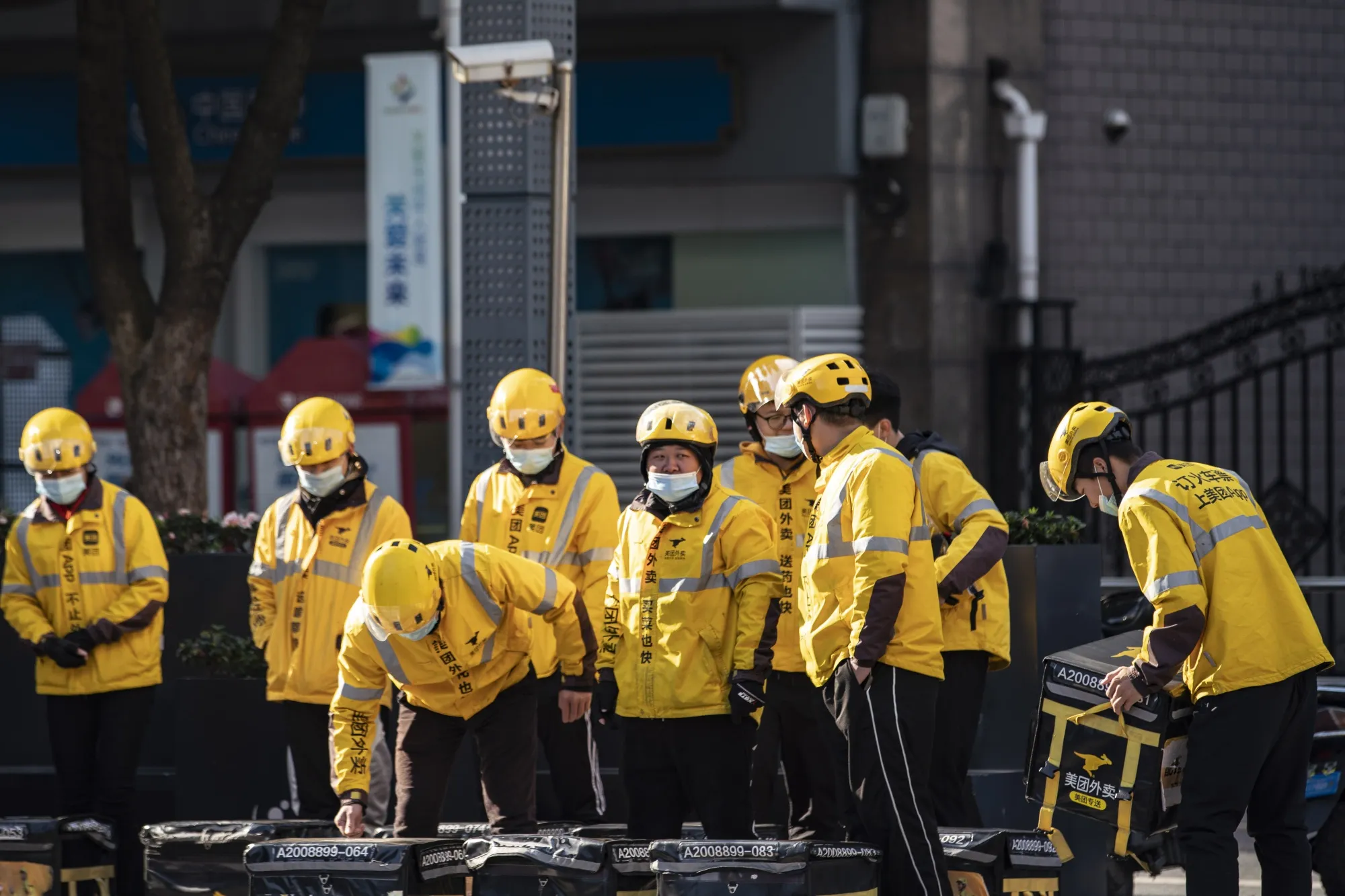 Food delivery couriers for Meituan during a morning briefing on a street in Shanghai.