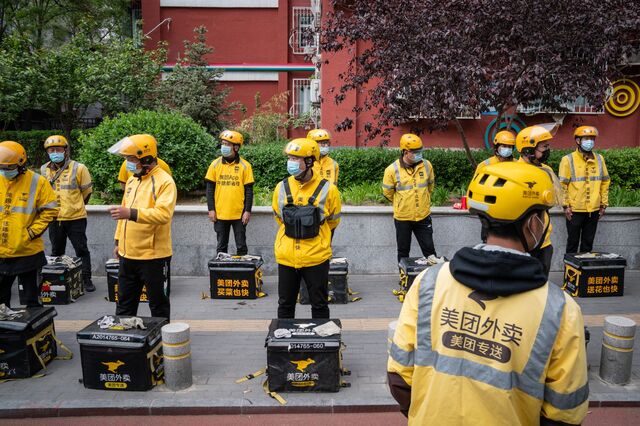 Food delivery couriers for Meituan stand with insulated bags during a morning briefing in Beijing, China, on Wednesday, April 21, 2021. Chinese delivery giant Meituan has raised $9.98 billion from a record top-up placement and a convertible bonds sale as it doubles down on efforts to fight the likes of Alibaba Group Holding Ltd. in newer areas such as online groceries.