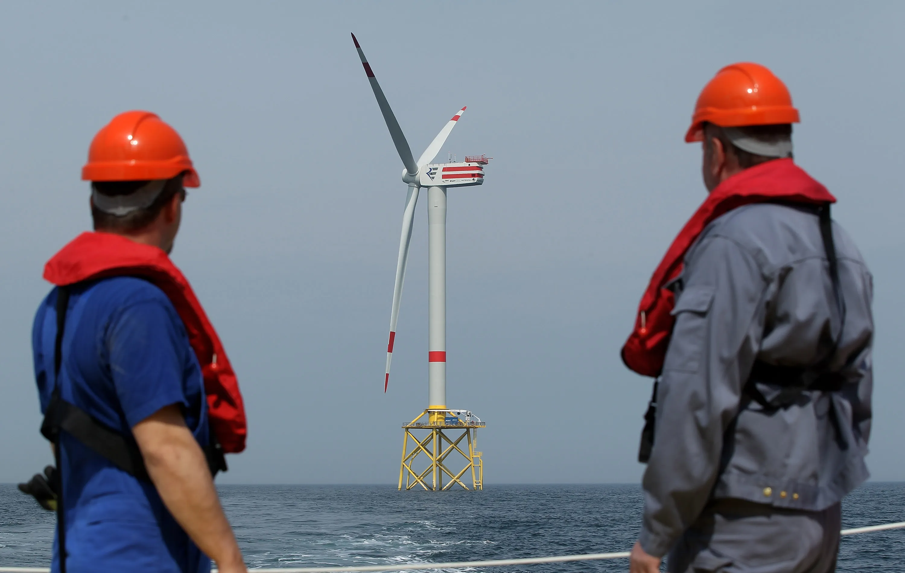 Workers look out at an offshore wind farm.