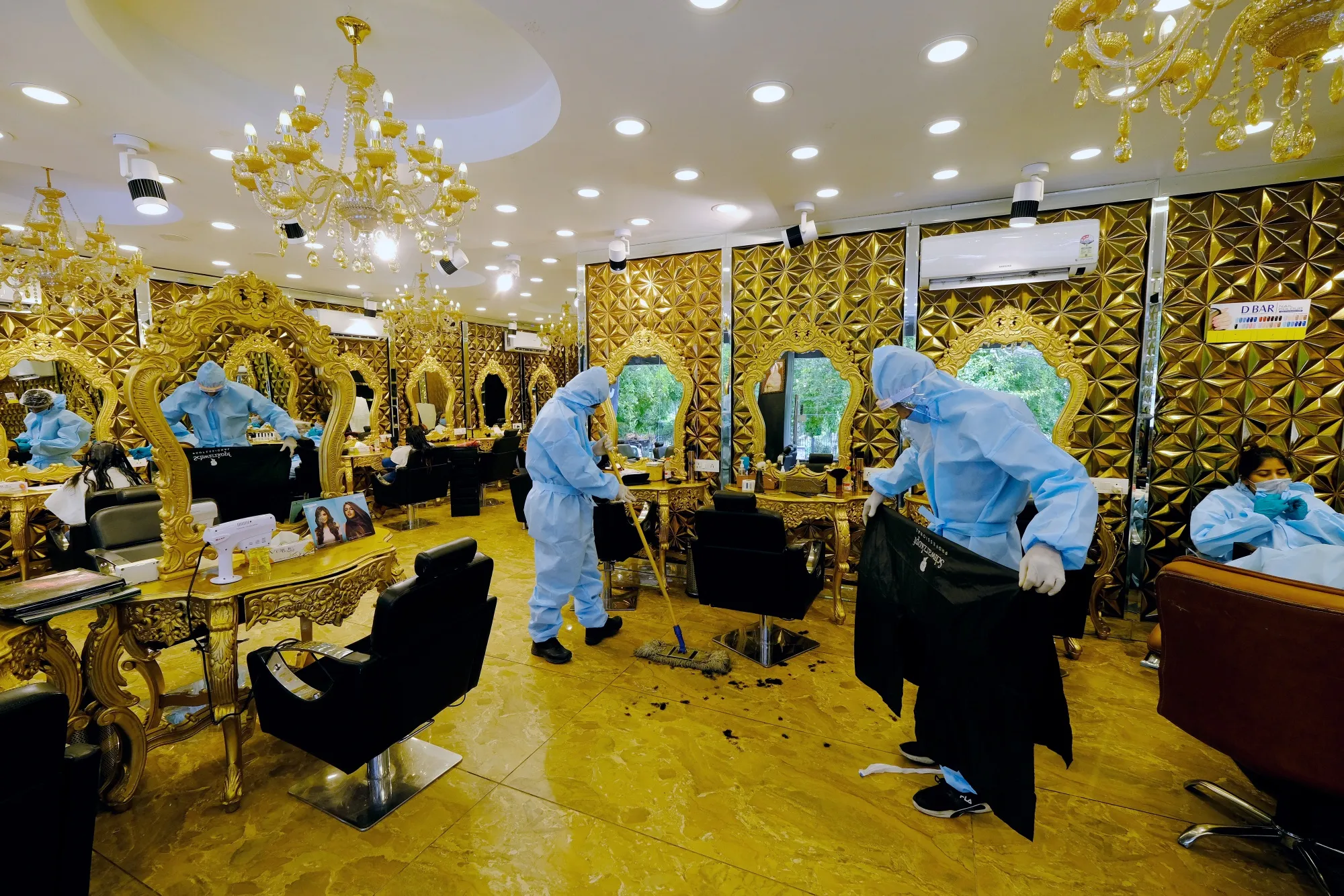 Hairdressers wearing protective clothing clean up at a hair salon in New Delhi, June 3.