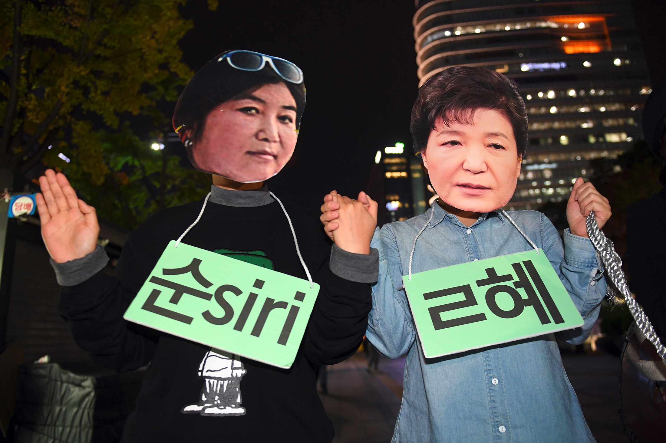 Protestors wearing masks of South Korean President Park Geun-Hye, right and Choi Soon-Sil pose for a performance in Seoul on Oct. 27. South Korean prosecutors on October 27 set up a high-powered 'task-force' to probe a widening scandal involving alleged influence-peddling by a close confidante of President Park Geun-Hye. Choi Soon-Sil, an enigmatic woman with no government position, was already part of an investigation into allegations that she used her relationship with the president to strong-arm conglomerates into multi-million dollar donations to two non-profit foundations. / AFP / JUNG YEON-JE (Photo credit should read JUNG YEON-JE/AFP/Getty Images)
