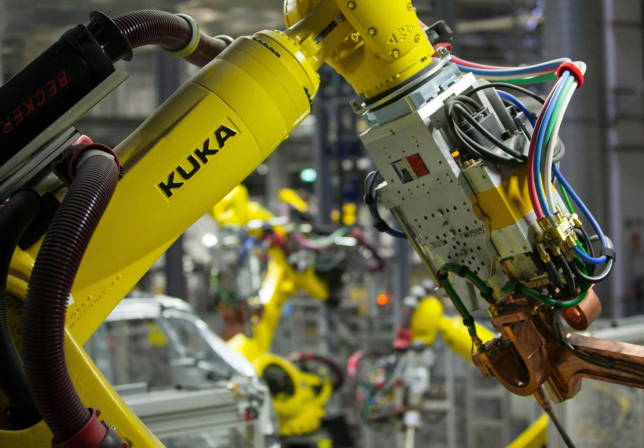 Robotic arms, manufactured by Kuka AG, operate on chassis of Porsche Macan sport-utility vehicles (SUV) on the production line inside the new Porsche AG factory in Leipzig, Germany, on Wednesday, Feb. 5, 2014.

