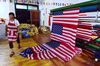 This photo taken on July 13, 2018 shows a Chinese employee walking past newly made US flags at a factory in Fuyang in China's eastern Anhui province. - As the Sino-US trade war rages, a factory set amid corn and mulberry fields in central China stitches together US and "Trump 2020" flags -- and business is good. (Photo by - / AFP) / China OUT (Photo credit should read -/AFP/Getty Images)