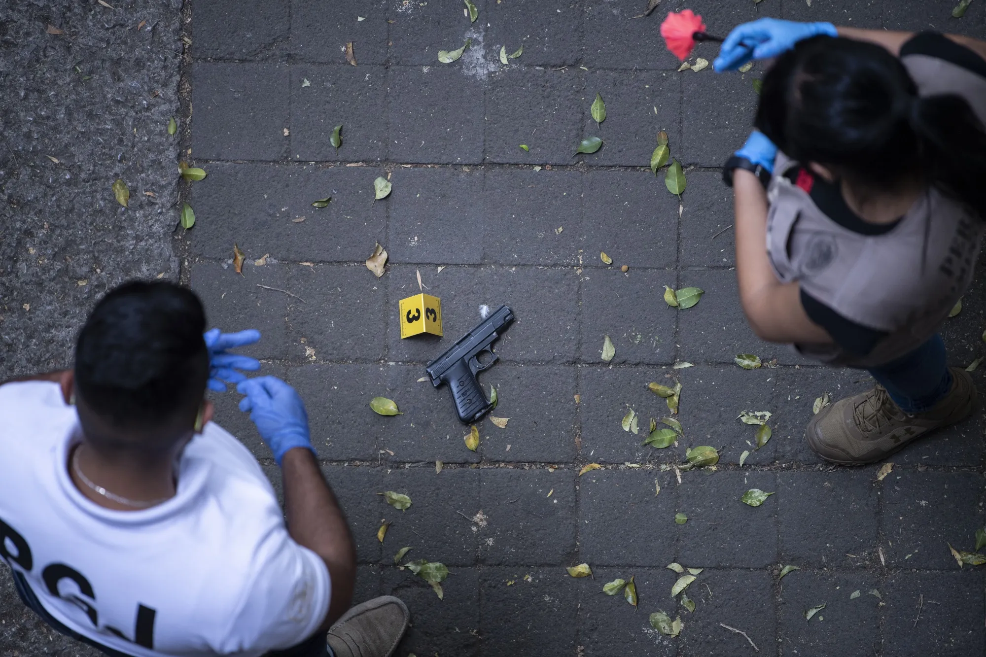 Mexican forensic experts observe a gun used on an assault in the La Condesa neighborhood of Mexico City, on May 6.