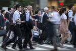 Commuters cross a road in the central business district of Tokyo, Japan,.