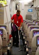 An employee vacuums an aisle carpet inside the economy class section of an Airbus A380-800 aircraft, operated by Emirates, as the plane is prepared for its next flight from Terminal 3 of Heathrow Airport in London, U.K., on Thursday, Dec. 5, 2013. 