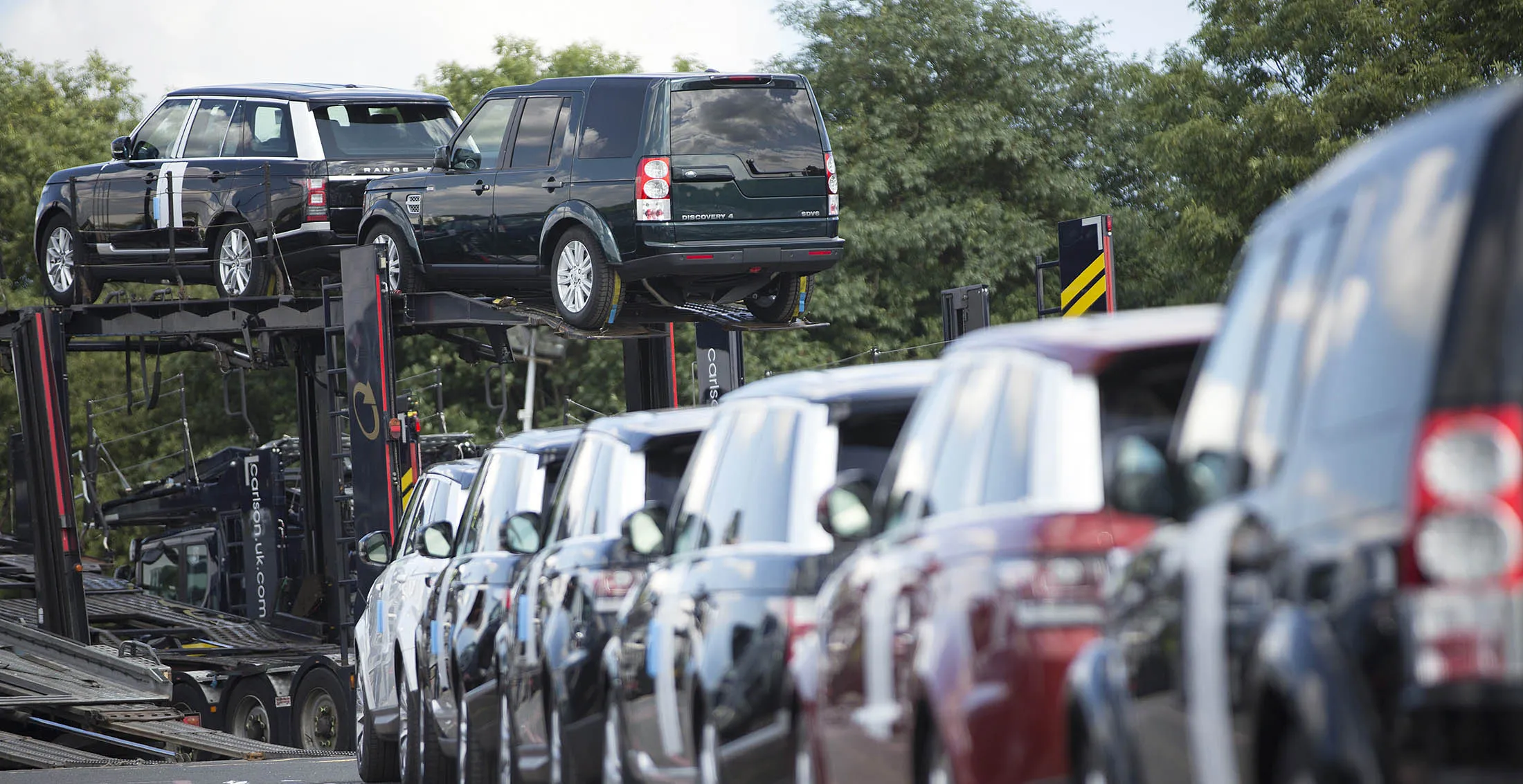 Ranger Rover and Land Rover automobiles line up ready for dispatch on a vehicle transporter at the Jaguar Land Rover Plc assembly plant in Solihull, U.K., on Wednesday, July 24, 2013. Tata Motors Ltd., India's biggest automaker, posted profit that beat analyst estimates as the Jaguar XF, Land Rover Freelander and the best-selling Evoque accounted for more than 50 percent of the luxury unit's sales.
