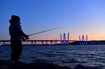 A man fishes off of rocks along the Hudson River near The Governor Mario M. Cuomo Bridge in Tarrytown, New York.