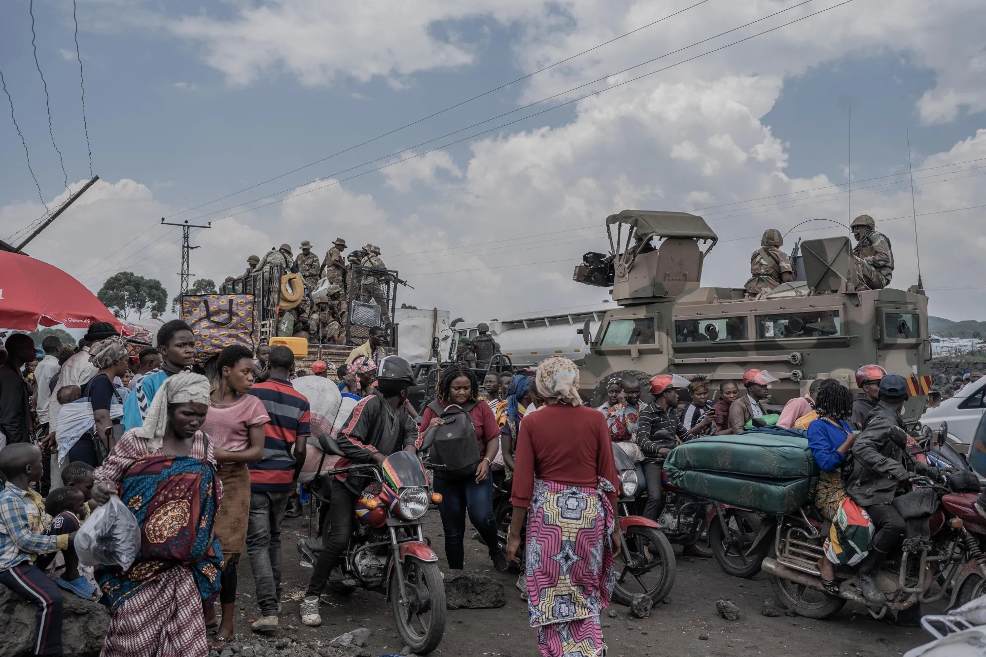 People gather next to some vehicles from the South African National Defence Force&nbsp;as part of the Southern African Development Community Mission in&nbsp;near Sake, Rwanda on Feb.&nbsp;7.