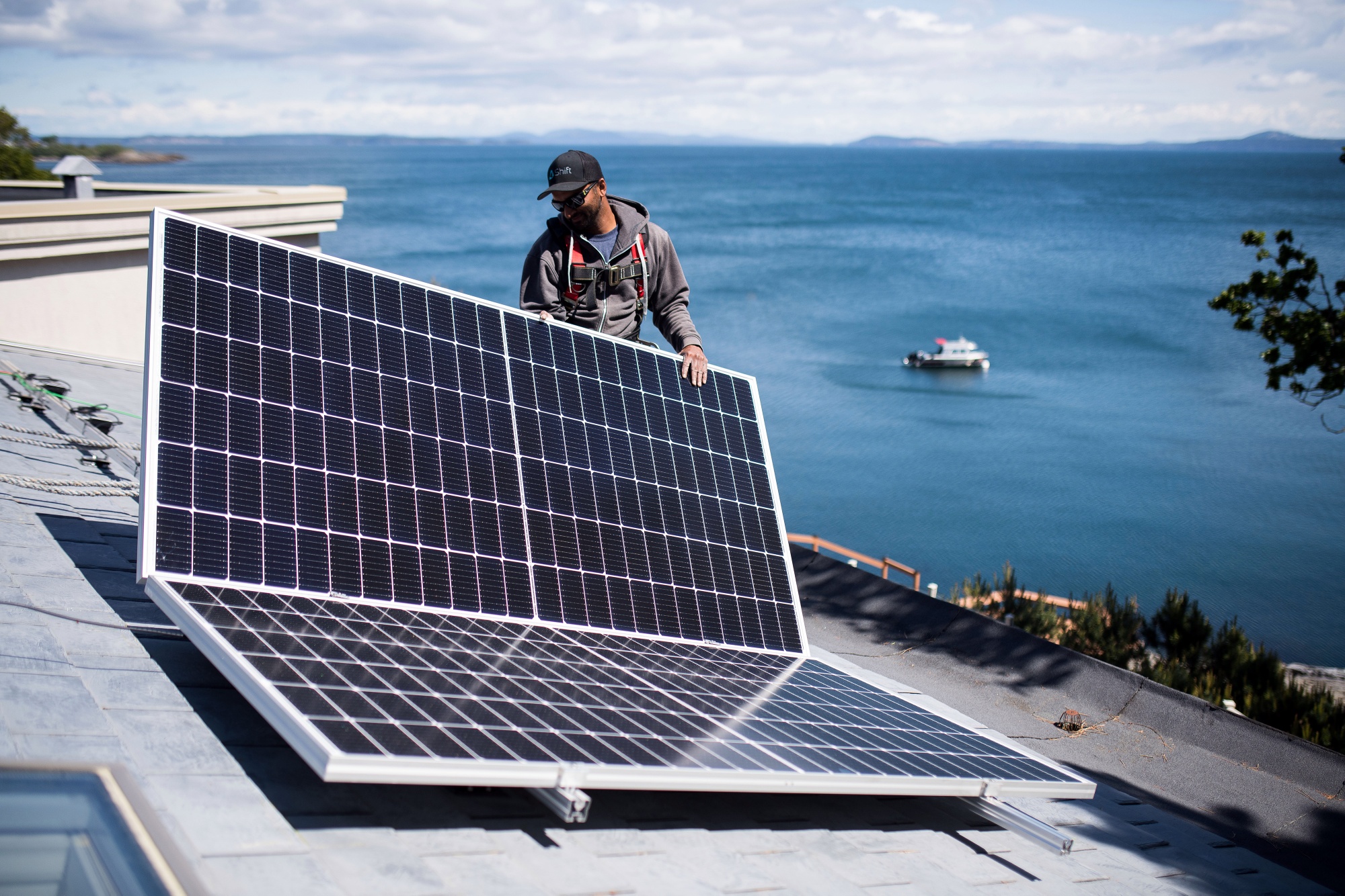 A worker places a solar panel on the roof of a home in Victoria, British Columbia.&nbsp;