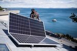 A worker places a solar panel on the roof of a home in Victoria, British Columbia. 