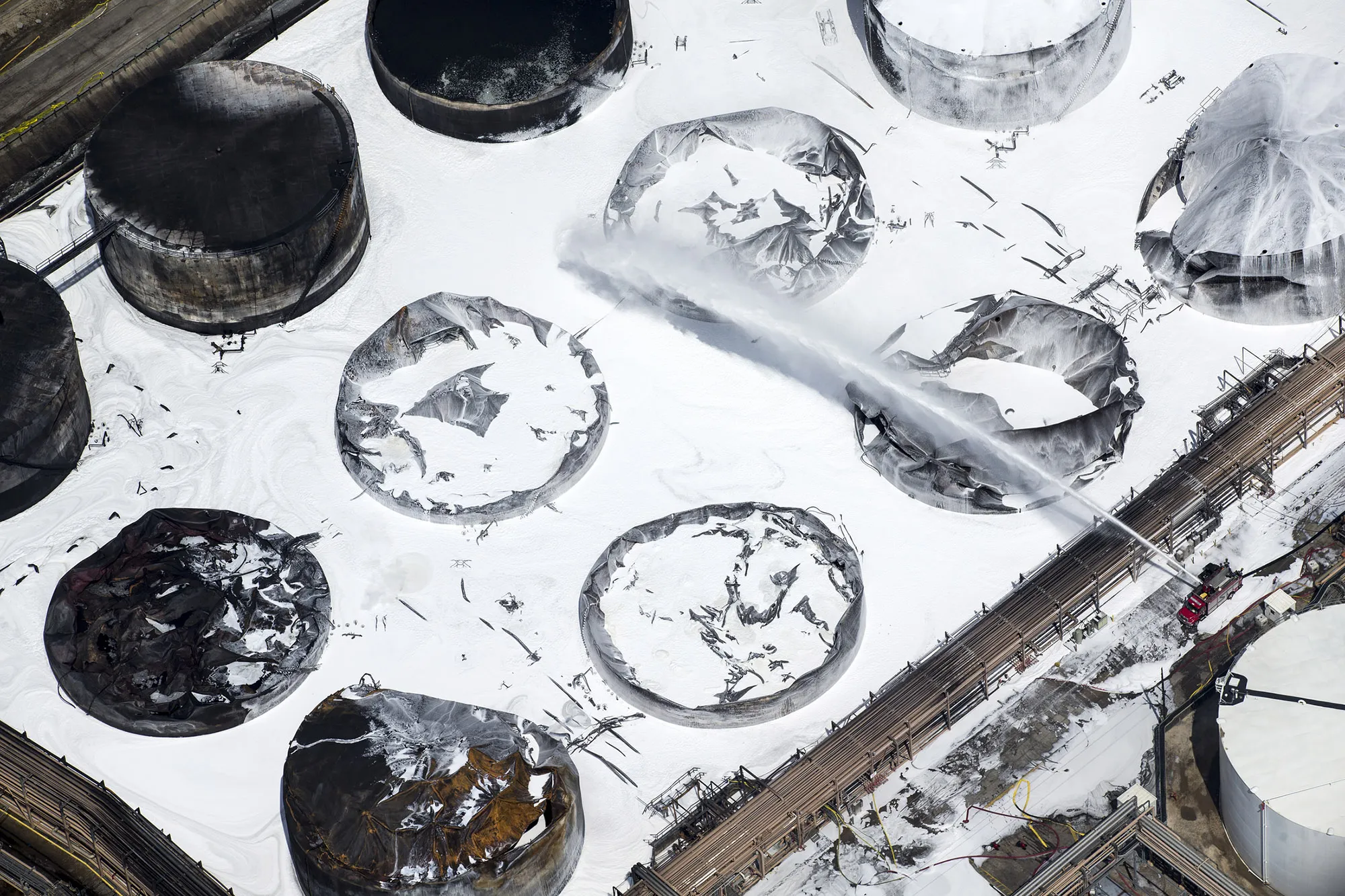 Emergency crews douse what’s left of the now-extinguished petrochemical tank fire on March 20.