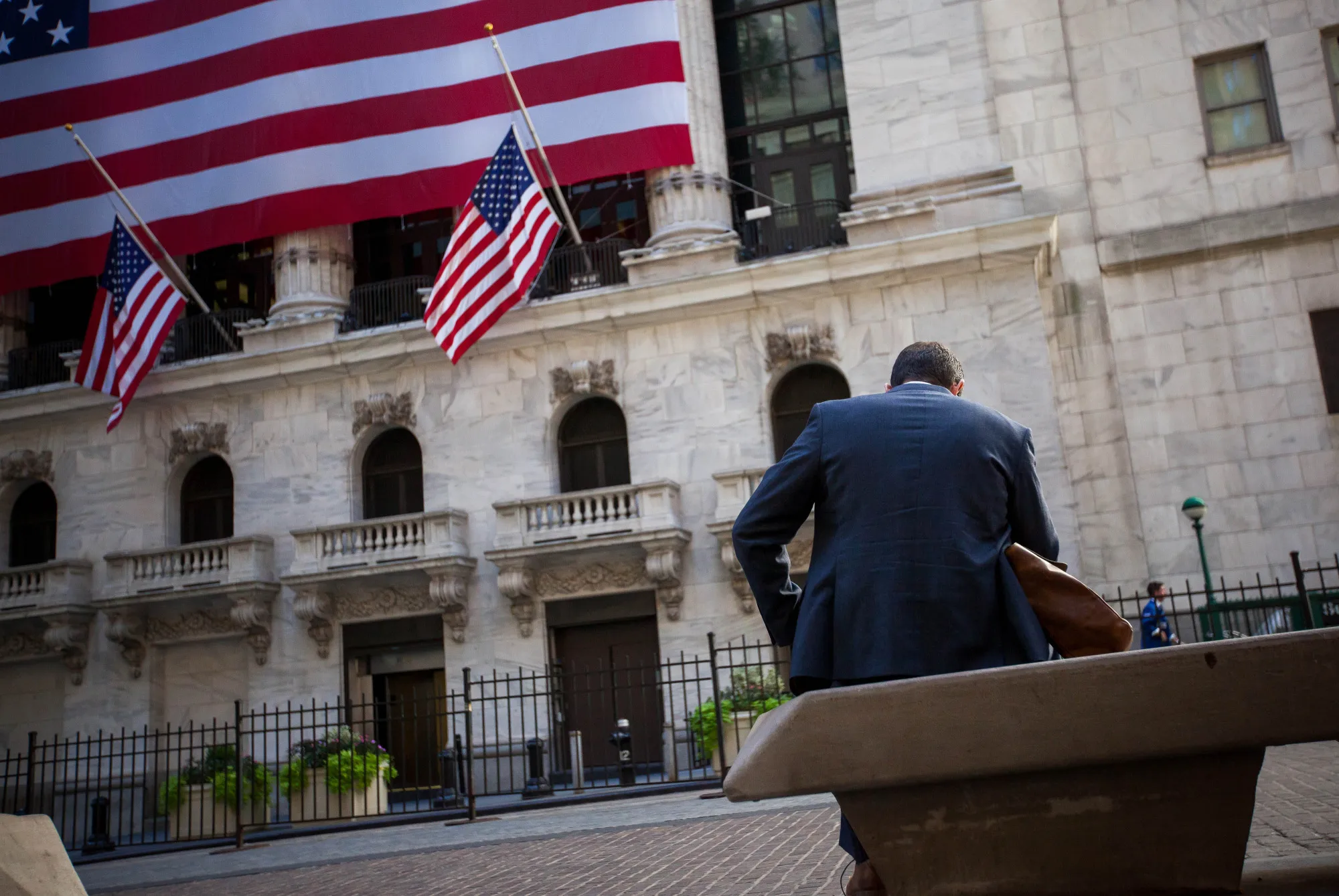 A man sits on a bench in front of the New York Stock Exchange (NYSE) in New York, U.S.