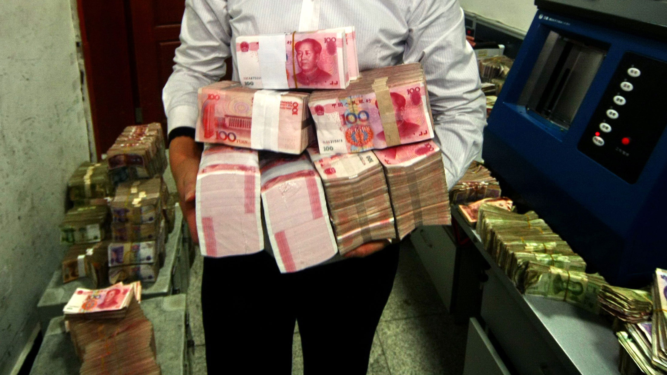 A clerk with stacks of Chinese 100-yuan notes at a bank in Suining, southwest China's Sichuan province.
