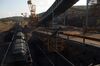 Crushed iron ore is transported in railroad cars, left, next to a conveyer belt at Vale SA's Brucutu mine in Barao de Cocais, Brazil. Bloomberg