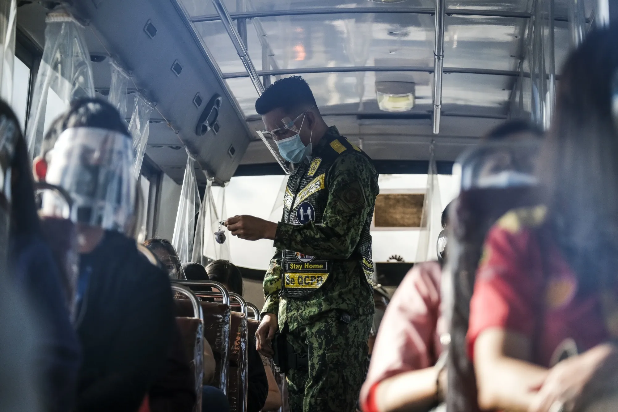 A member of the Philippine National Police checks the identification of bus passengers crossing the border from Rizal Province into Quezon City, Metro Manila,&nbsp;on Aug. 6.