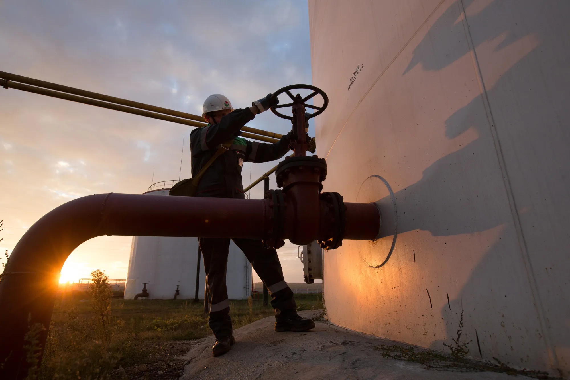 A control valve on pipework beside a storage tank at an oil delivery point.&nbsp;