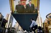 People bicycle past a giant TV screen broadcasting the meeting of North Korean leader Kim Jong Un and Chinese President Xi Jinping .
