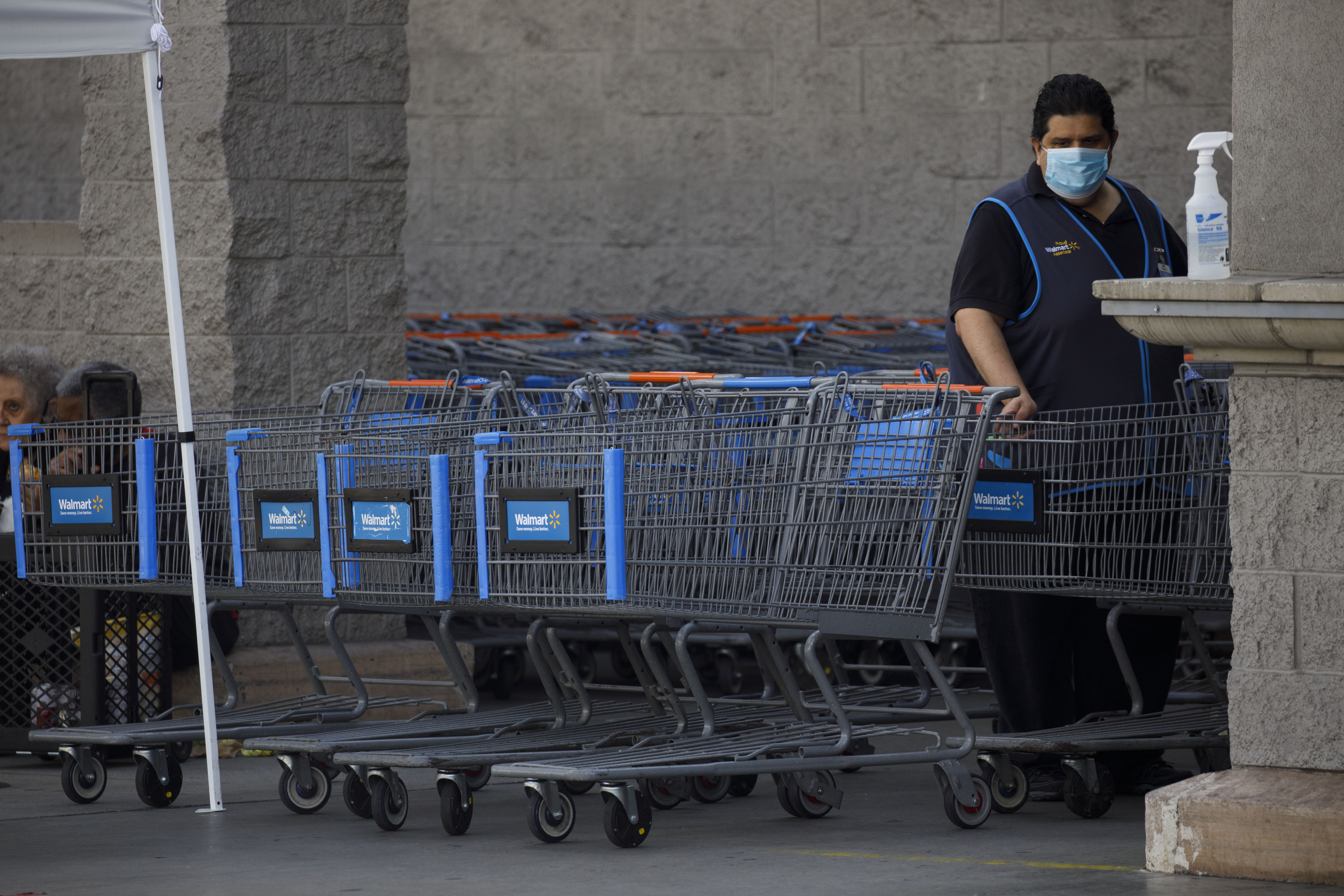 An employee cleans shopping carts outside of a Walmart in Torrance, California, on May 19, 2020.