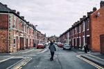 A pedestrian crosses a street of terraced residential housing in Wallsend, U.K.